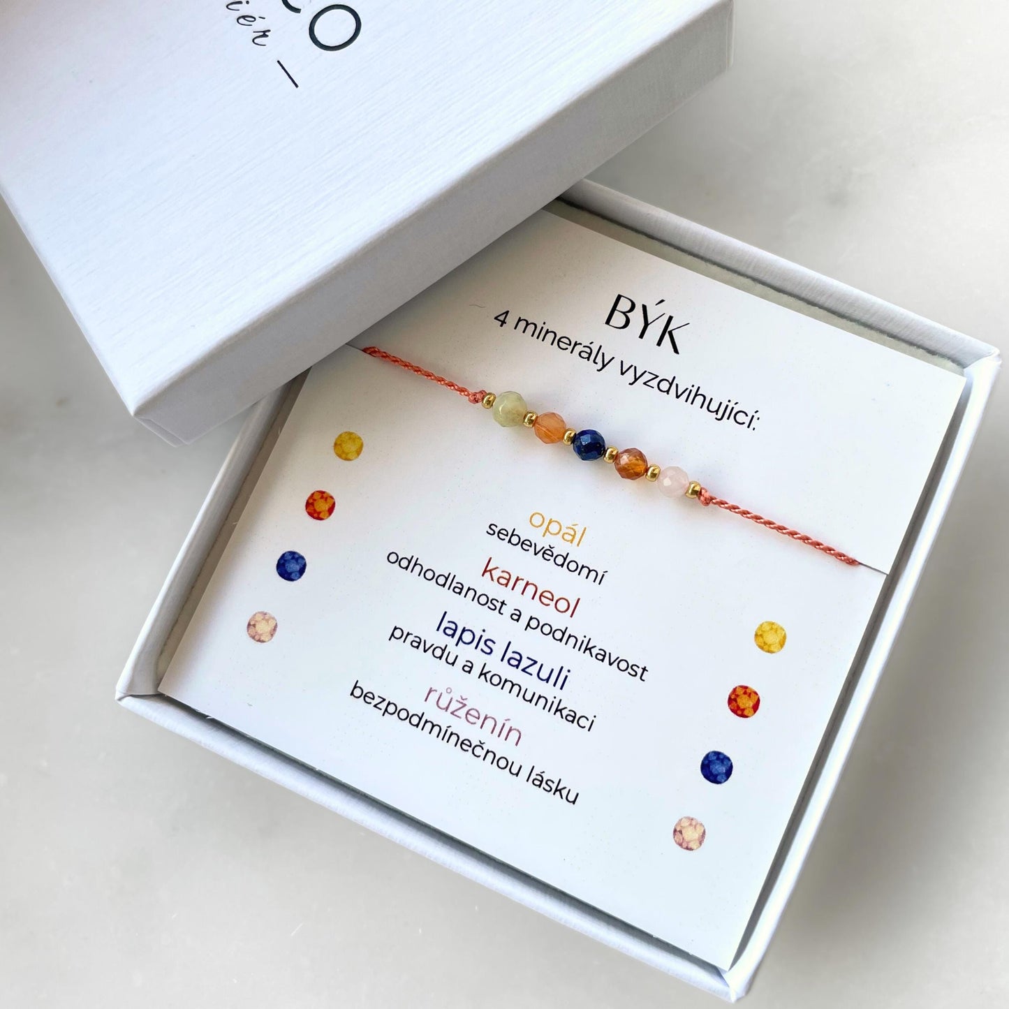 Bílá krabička, ve které je náramek vytvořený z hedvábného provázku a pěti minerály. Náramek je upevněn na promo kartičce s nápisem Býk. Náramek je udělán na téma Znamení Zvěrokruhu. Karta také obsahuje vysvětlivky ke každému použitému kameni: Opál pro Sebevědomí, Karneol pro Odhodlanost a Podnikavost, Lapis Lazuli pro Pravdu a Komunikaci, Růženín pro Bezpodmínečnou Lásku