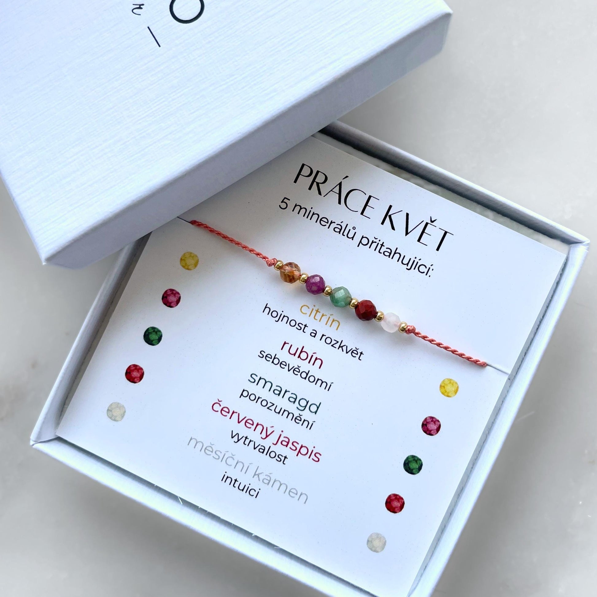 Bílá krabička, ve které je náramek vytvořený z hedvábného provázku a pěti minerály. Náramek je upevněn na promo kartičce s nápisem Práce Květ. Náramek je udělán na téma Pracovní Úspěch. Karta také obsahuje vysvětlivky ke každému použitému kameni: Citrín pro Hojnost a Rozkvět, Rubín pro Sebevědomí, Smaragd pro Porozumění, Červený Jaspis pro Vytrvalost, Měsíční Kámen pro Intuici