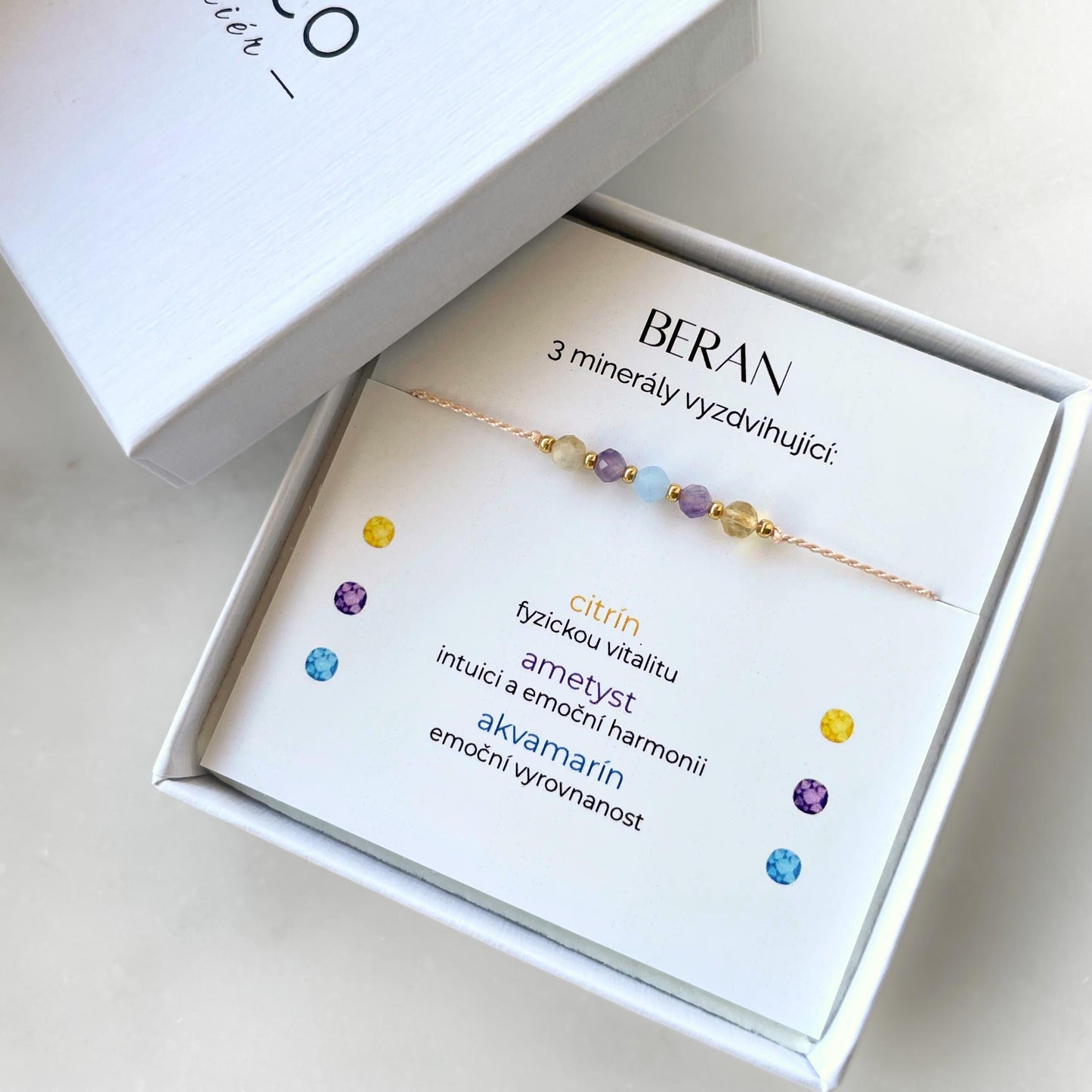 Bílá krabička, ve které je náramek vytvořený z hedvábného provázku a pěti minerály. Náramek je upevněn na promo kartičce s nápisem Beran. Náramek je udělán na téma Znamení Zvěrokruhu. Karta také obsahuje vysvětlivky ke každému použitému kameni: Citrín pro Fyzickou Vitalitu, Ametyst pro Intuici a Emoční Harmonii, Akvamarín pro Emoční Vyrovnanost