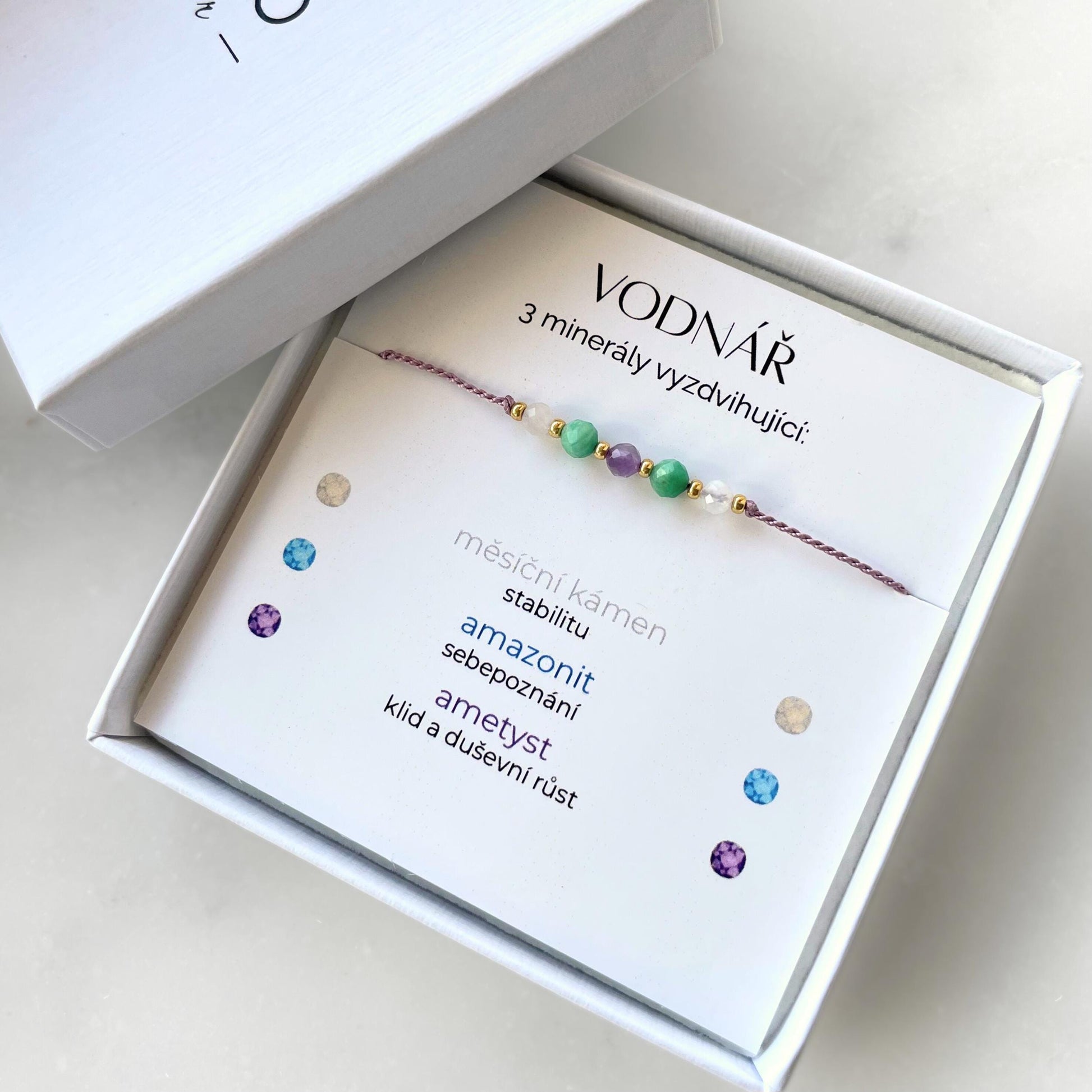 Bílá krabička, ve které je náramek vytvořený z hedvábného provázku a pěti minerály. Náramek je upevněn na promo kartičce s nápisem Vodnář. Náramek je udělán na téma Znamení Zvěrokruhu. Karta také obsahuje vysvětlivky ke každému použitému kameni: Měsíční Kámen pro Stabilitu, Amazonit pro Sebepoznání, Ametyst pro Klid a Duševní Růst
