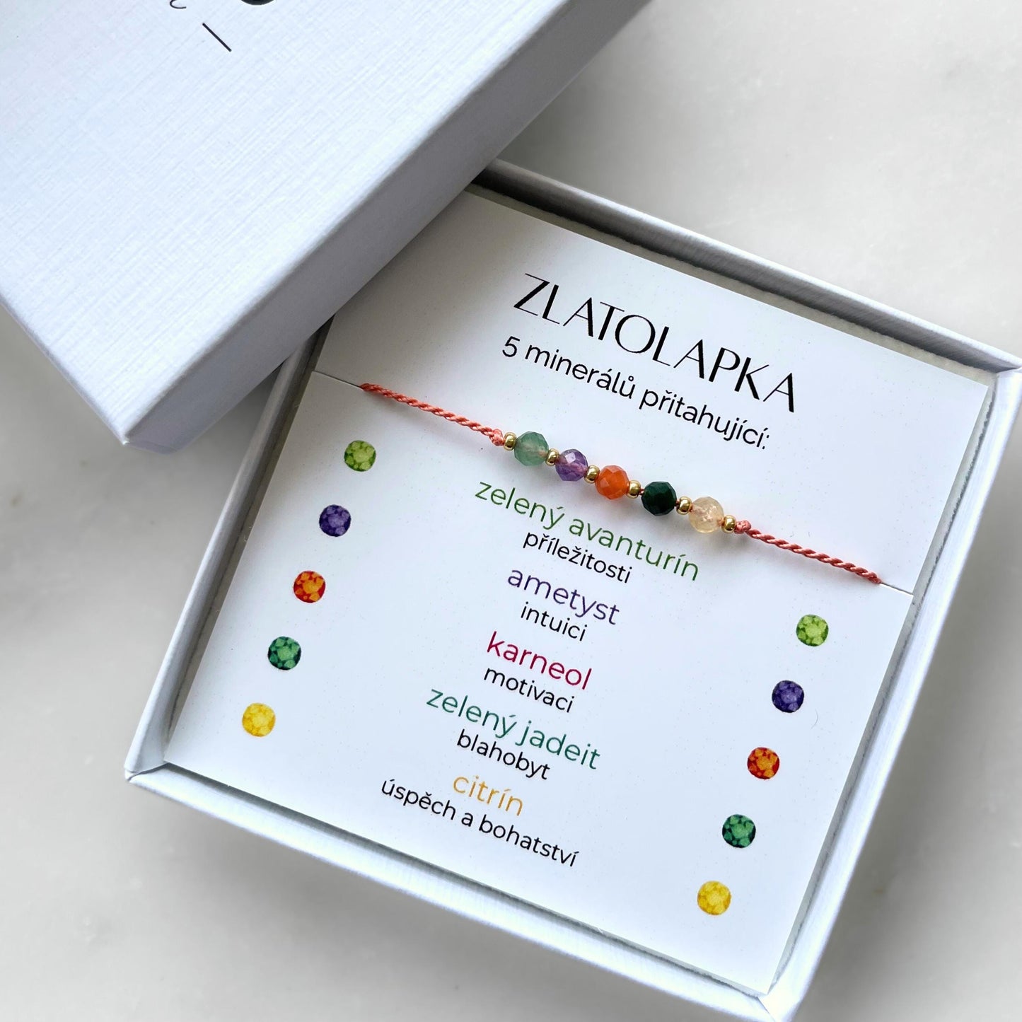 Bílá krabička, ve které je náramek vytvořený z hedvábného provázku a pěti minerály. Náramek je upevněn na promo kartičce s nápisem Zlatolapka. Náramek je udělán na téma Bohatství. Karta také obsahuje vysvětlivky ke každému použitému kameni: Zelený Avanturín pro Příležitosti, Ametyst pro Intuici, Karneol pro Motivaci, Zelený Jadeit pro Blahobyt, Citrín pro Úspěch a Bohatství