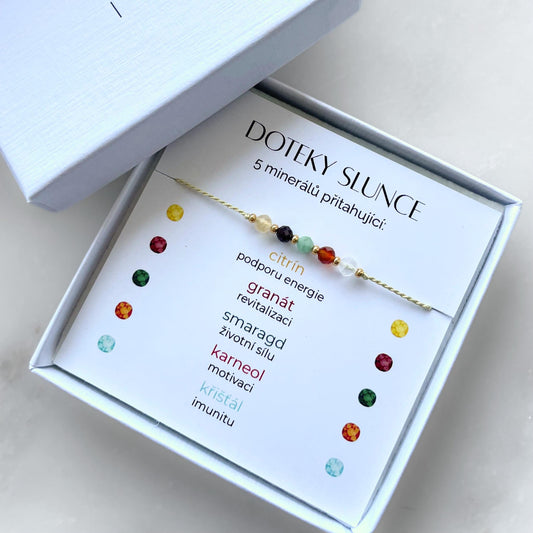 Bílá krabička, ve které je náramek vytvořený z hedvábného provázku a pěti minerály. Náramek je upevněn na promo kartičce s nápisem Doteky Slunce. Náramek je udělán na téma Vitalita. Karta také obsahuje vysvětlivky ke každému použitému kameni: Citrín pro Podporu Energie, Granát pro Revitalizaci, Smaragd pro Životní Sílu, Karneol pro Motivaci, Křišťál pro Imunitu