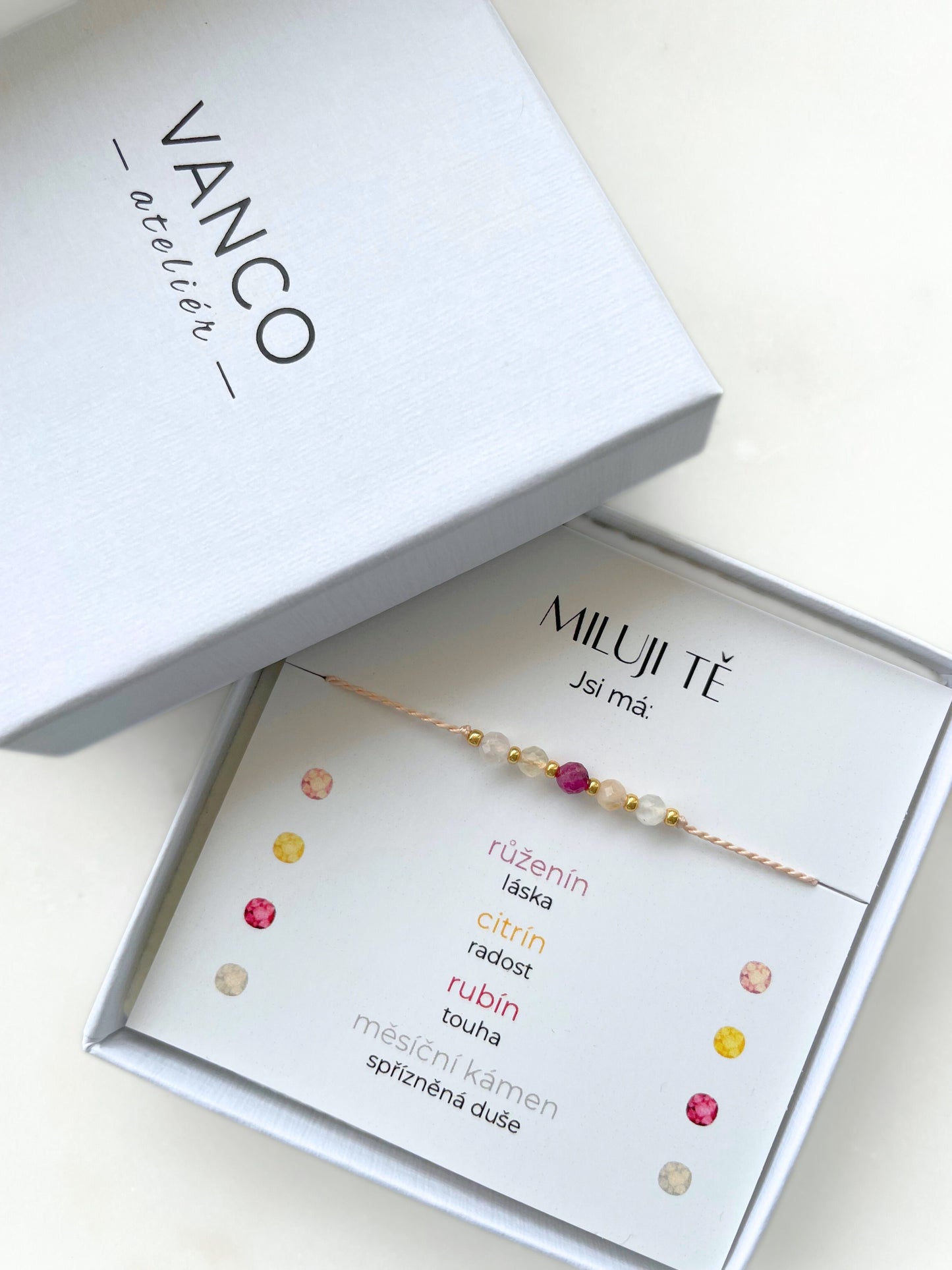 Náramek "Miluji tě" na růžové šňůrce s růženínem, rubínem, měsíčním kamenem, citrínem a zlatými korálky v bílém dárkovém balení.